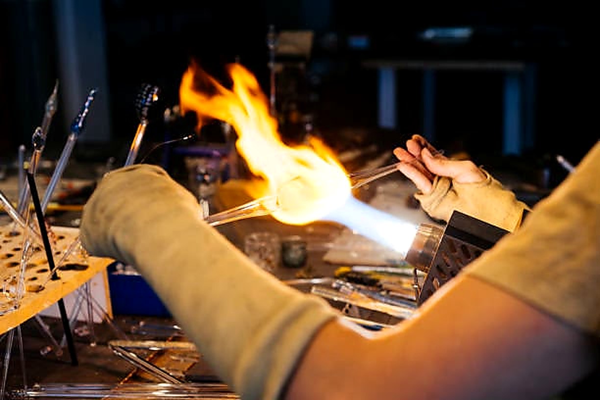 A glassmaker shaping molten glass in the flame of a torch